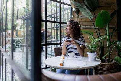 Woman looking through window at cafe
