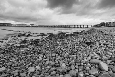 Surface level of stones on beach against sky including tay rail bridge