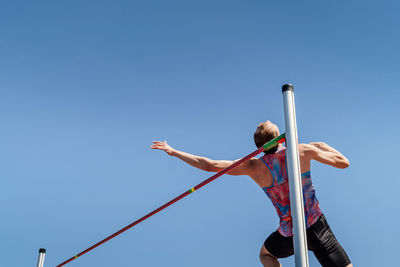 High jump male athlete on blue sky background