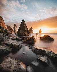 Scenic view of rocks in sea against sky during sunset