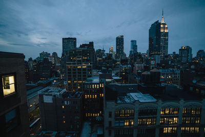 Illuminated buildings in city against sky at dusk