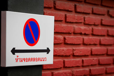 Close-up of arrow sign on brick wall