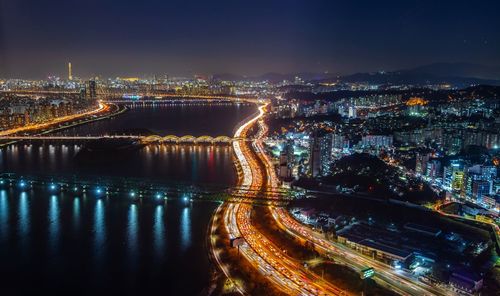 High angle view of illuminated city by river at night