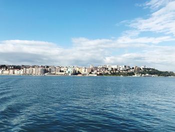 Scenic view of sea by buildings against sky