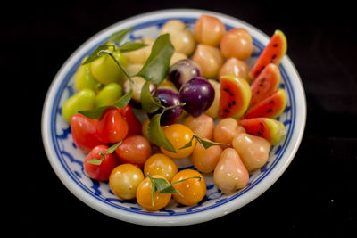 Close-up of fruits and vegetables in plate against black background