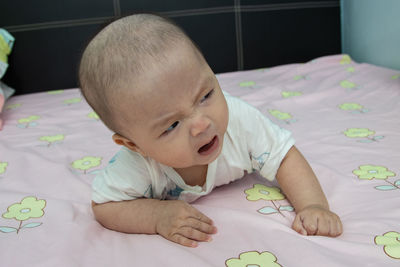 Cute baby girl lying on bed at home