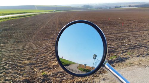 Reflection of field and sky in side-view mirror