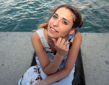 Portrait of smiling young woman sitting in sea