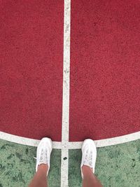 Low section of person wearing white sports shoes standing on court