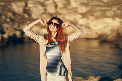 Portrait of woman wearing sunglasses standing against sea