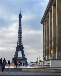 Tourists looking at eiffel tower against cloudy sky