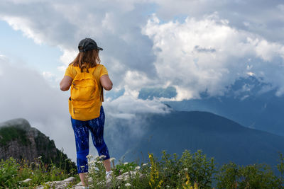Rear view of woman standing on mountain against sky