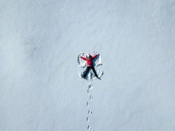 Directly above shot of woman lying down on snow