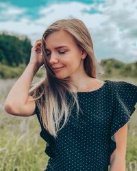 Portrait of beautiful young woman standing on field