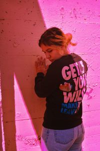 Woman standing by pink wall