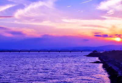 Bridge over river against sky during sunset