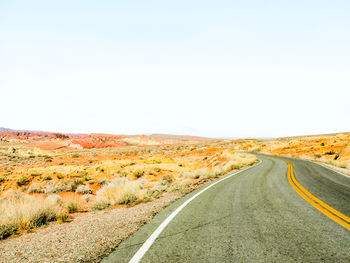 Road passing through landscape against clear sky