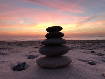 Stack of stones at beach during sunset