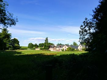 Trees and farmer's houseon field against sky