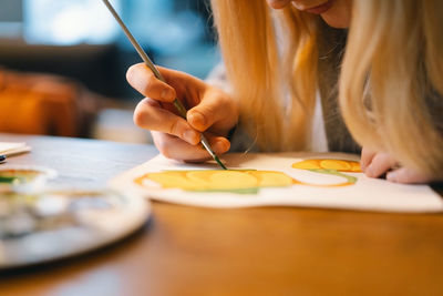 Pretty teenage girl draws a picture with poster paint.