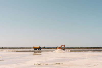 Spain, province of huelva, huelva, clear sky over truck and earth mover working in salt flat
