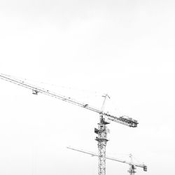 Low angle view of cranes against clear sky