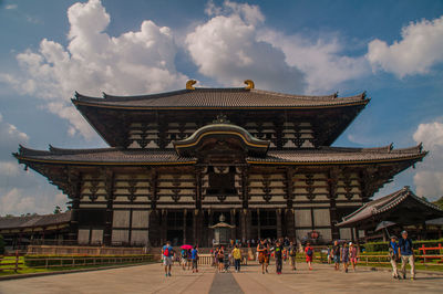 People at temple against cloudy sky