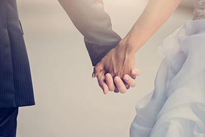 Midsection of couple holding hands