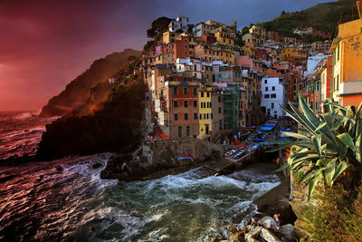 Scenic view of sea by cinque terre against cloudy sky at sunset