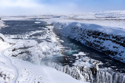 Scenic view of snowcapped waterfall against sky