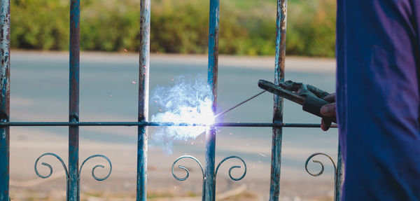 Close-up of metal fence against blue water