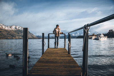 Man standing on pier over sea against sky