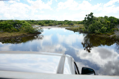 Cropped image of car at lakeshore against sky