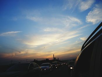 Cars on road against sky during sunset