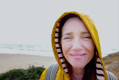 Portrait of smiling young woman at beach against sky