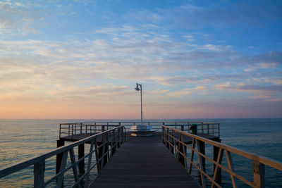 Pier over sea against sky during sunset