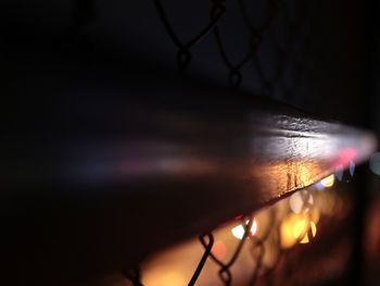 Close-up of chainlink fence against sky at night