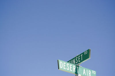 Low angle view of road sign against clear blue sky