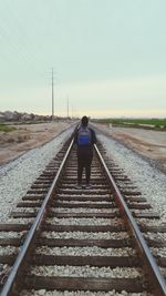 Rear view of woman walking on railroad track