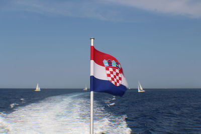 Flag on sea against sky