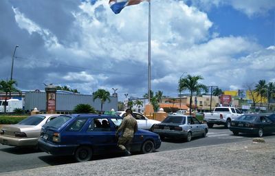 Cars on road against cloudy sky