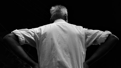 Rear view of man standing against black background