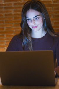 Portrait of young woman using laptop at home