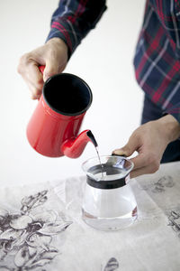 Cropped image of man pouring water in jug at table