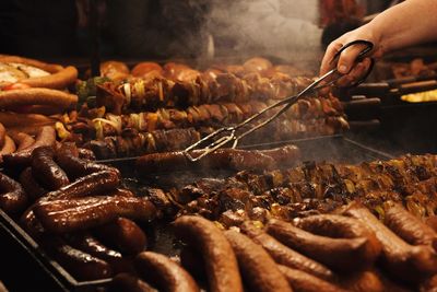 Cropped image of person preparing meat on barbecue grill