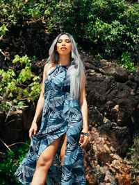 Portrait of young trans woman standing against trees