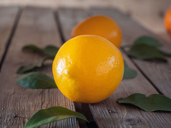 Fragrant big lemon and green leaves on wooden table close up blurred focus