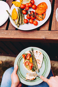 High angle view of hand holding fruit in plate on table