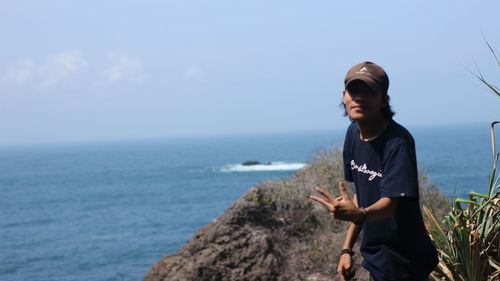 Young man standing in sea against sky