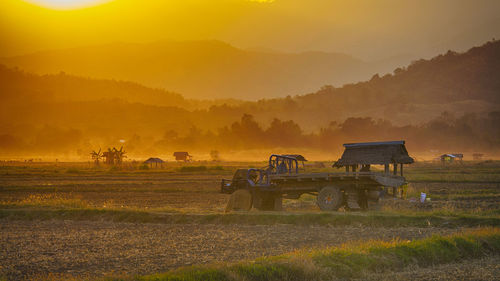 Scenic view of farm against mountains during sunset